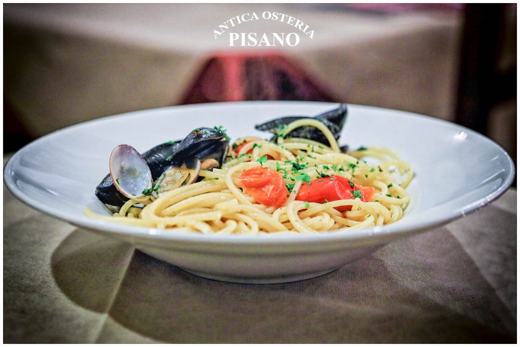 Spaghetti con cozze e pomodorini rossi, profumati di prezzemolo e aglio, serviti in un piatto bianco di Antica Osteria Pisano