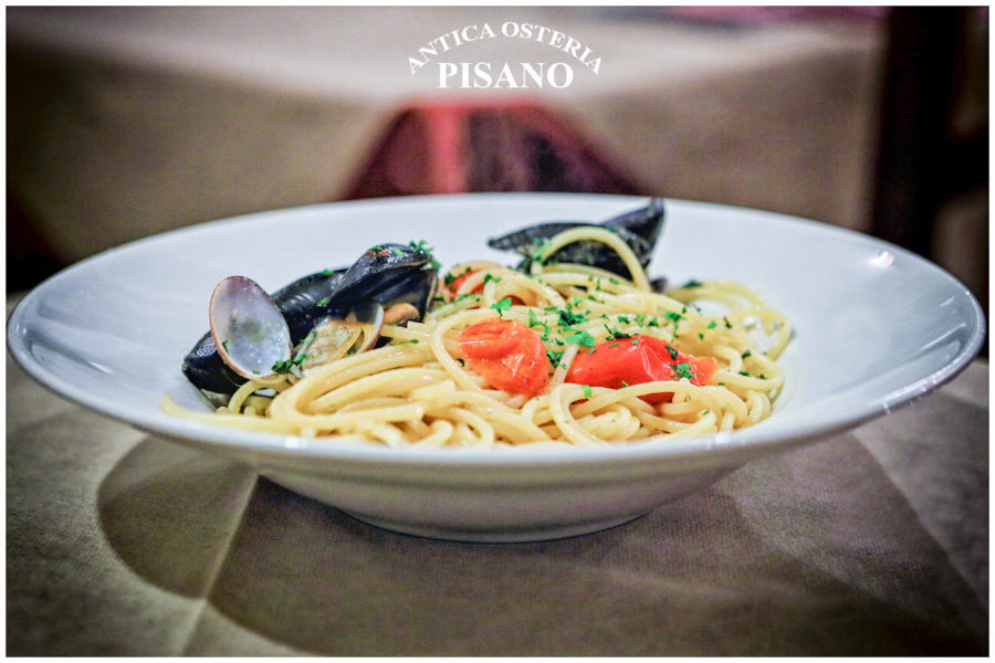 Spaghetti con cozze e pomodorini rossi, profumati di prezzemolo e aglio, serviti in un piatto bianco di Antica Osteria Pisano