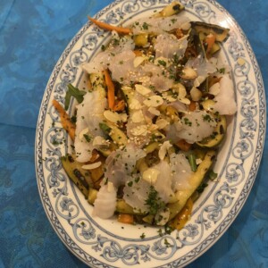 Insalata di pesce bianco con verdure e mandorle su piatto decorato Piatto di pesce bianco a lamelle con verdure colorate, mandorle a lamelle e prezzemolo su piatto decorato blu, stile cucina napoletana, alimento fresco e leggero