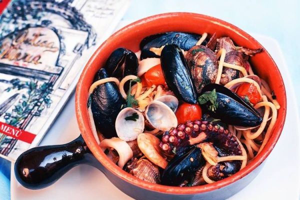 Pasta ai frutti di mare in ciotola di terracotta rossa, con cozze, vongole, calamari e pomodorini, pranzo di cucina tipica napoletana presso Antica Osteria Pisano